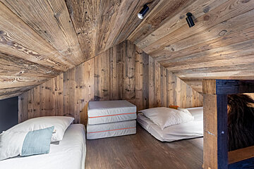 A bedroom with a wooden ceiling and two beds