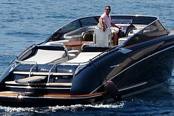 A man sits on the front of a boat that says ruffian