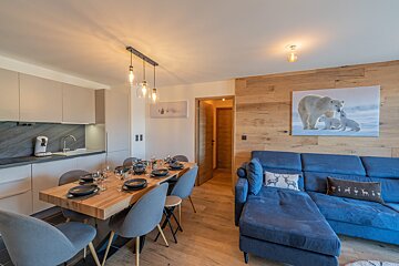 A living room with a blue couch and a picture of a polar bear on the wall