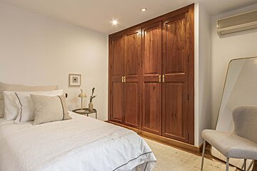 A bedroom with a bed a chair and a mirror
