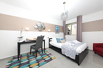 A bedroom with a bed a desk and a chair