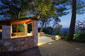 A stone structure with a wooden roof is lit up at night