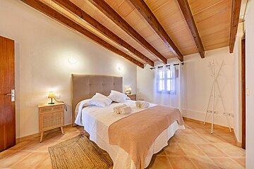 A bedroom with a wooden ceiling and a bed
