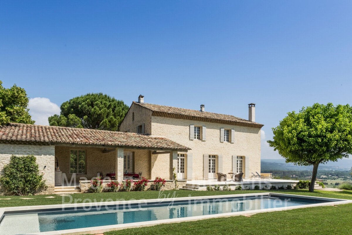 A large stone house with a large swimming pool in front of it