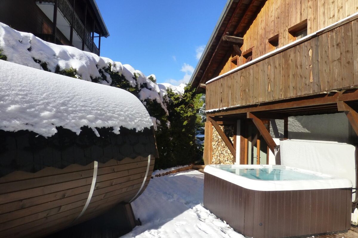 A hot tub sits outside of a snow covered building