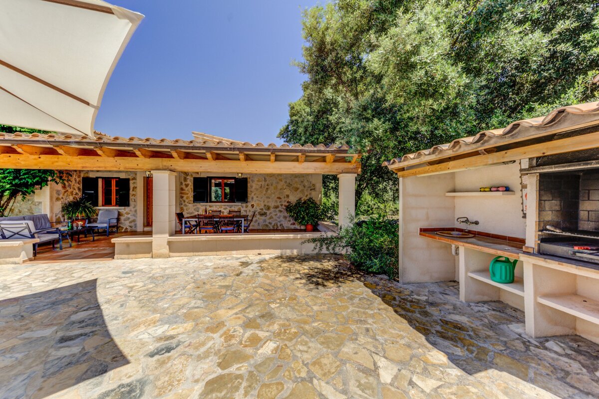 A green watering can sits in front of a barbecue area