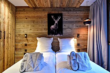 A bedroom with two beds and a painting of a deer on the wall