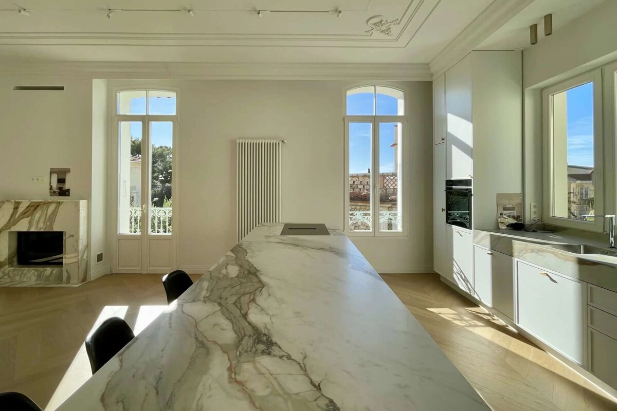 A kitchen with a marble counter top and white cabinets