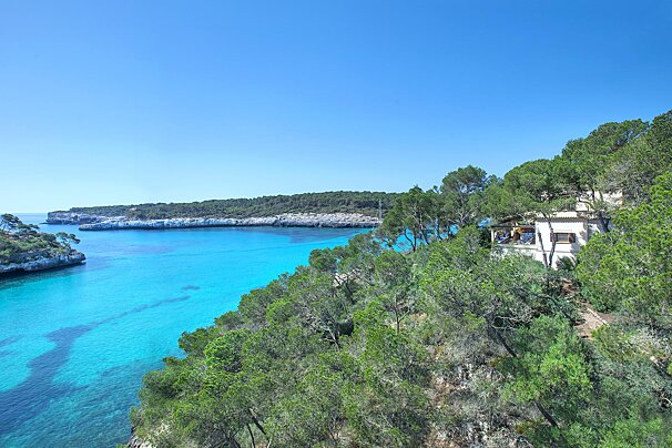A house sits on a hill overlooking a body of water
