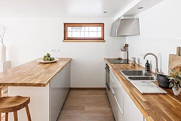 A kitchen with wooden counter tops and white cabinets