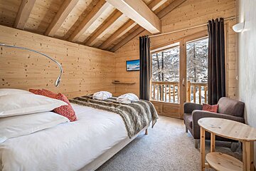 A bedroom with a large bed and a chair