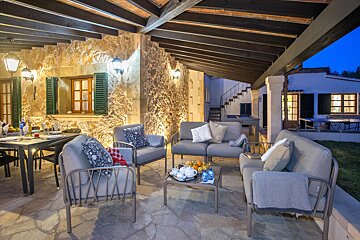 A patio with a couch and chairs under a wooden roof