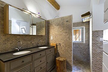 A bathroom with two sinks and a walk in shower