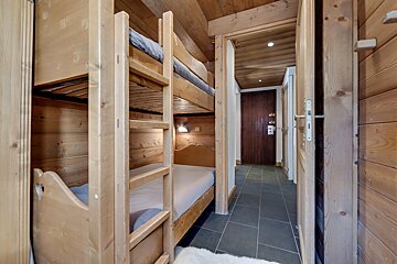A wooden bunk bed in a room with a door