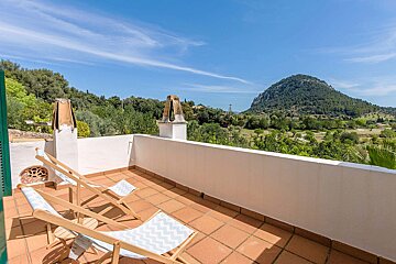 A balcony with chairs and a mountain in the background