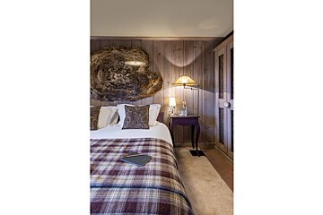 A bedroom with a plaid blanket on the bed
