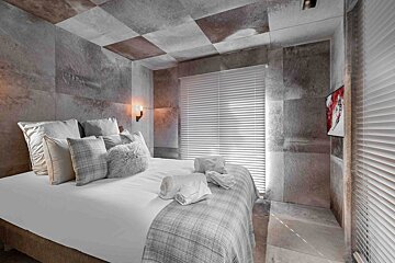 A bedroom with a bed and a tv on the wall