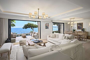 A living room with white furniture and a view of the ocean