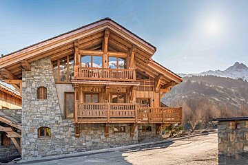 A large wooden house with mountains in the background