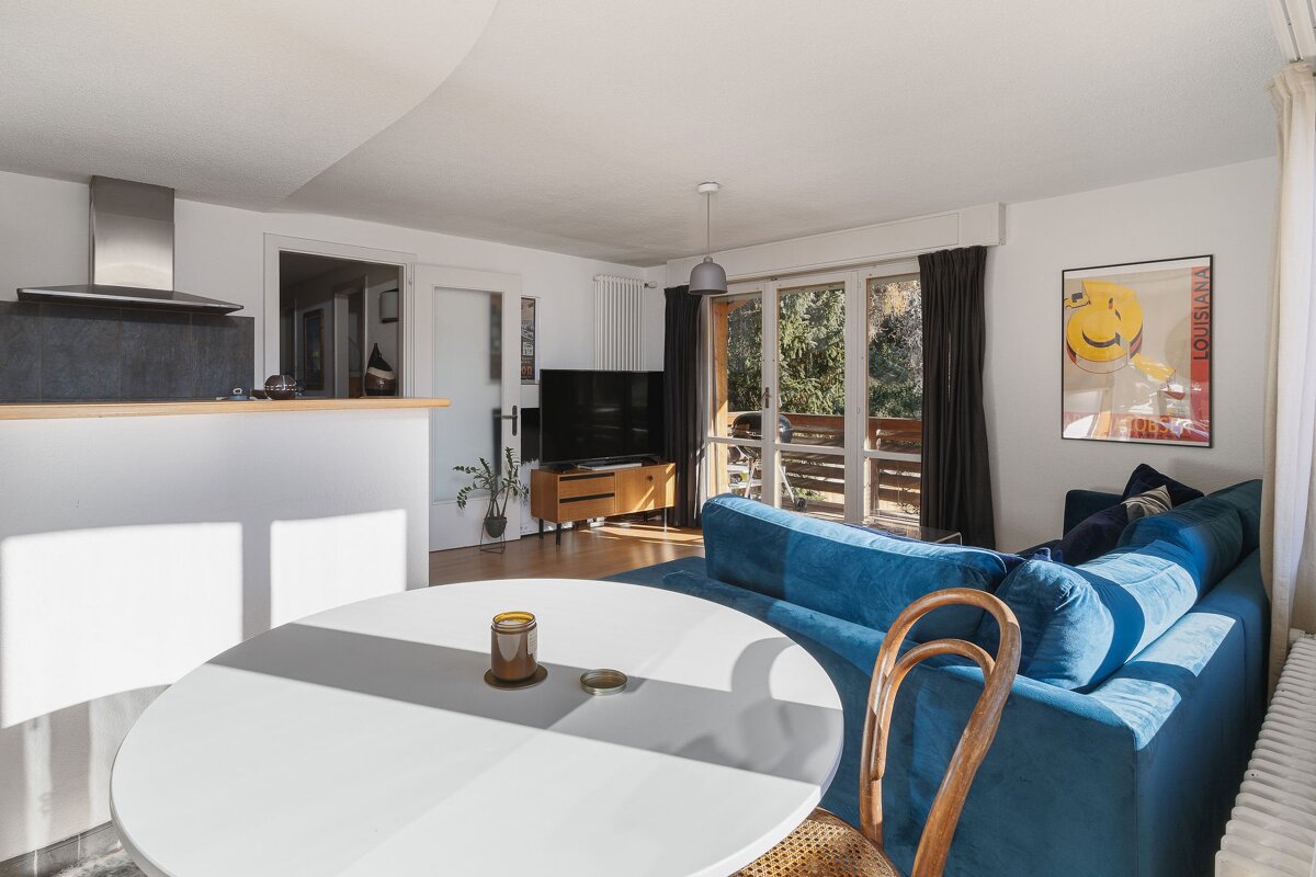 A living room with a blue couch and a white table