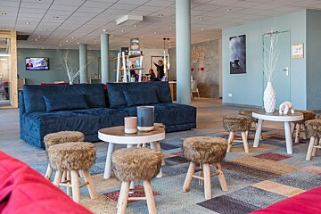 A living room with a blue couch and furry stools