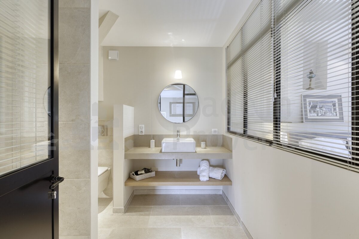 A bathroom with a sink and a round mirror