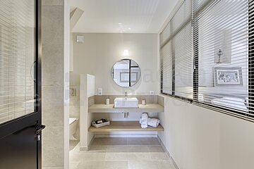 A bathroom with a sink and a round mirror