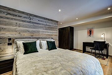 A bedroom with a bed a desk and a picture on the wall