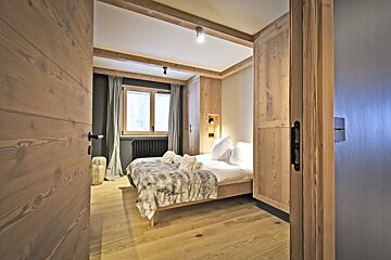A bedroom with a wooden door and a bed