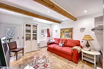 A living room with a red couch and a lamp
