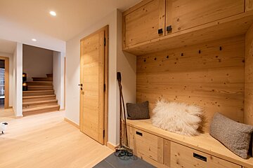 A wooden bench in a hallway with stairs in the background