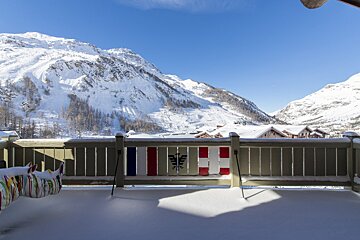 A snowy balcony with a french flag on the railing