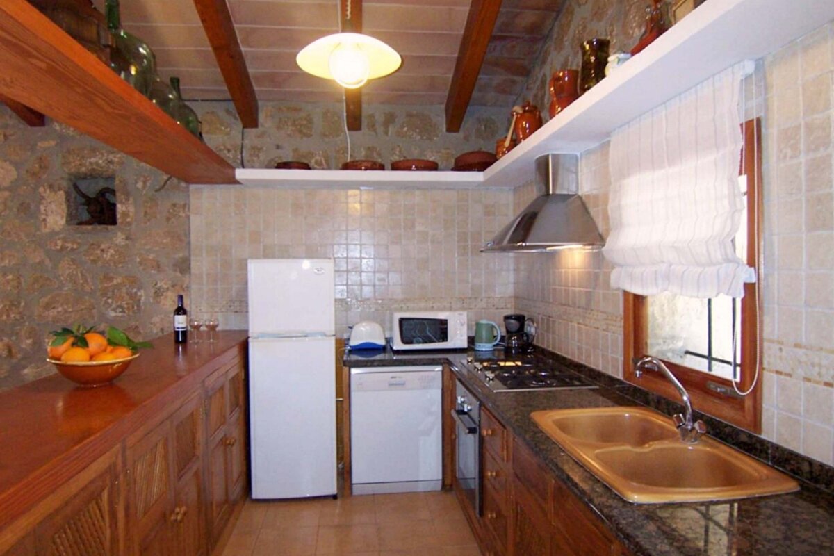 A kitchen with a bowl of oranges and a bottle of wine