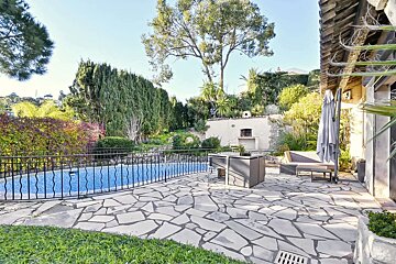 A stone patio with a swimming pool in the background