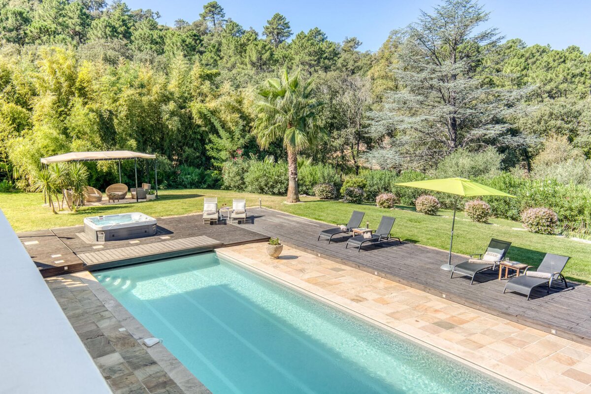 A large swimming pool surrounded by chairs and umbrellas