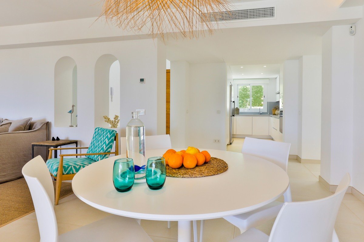 A white table with a bowl of oranges on it
