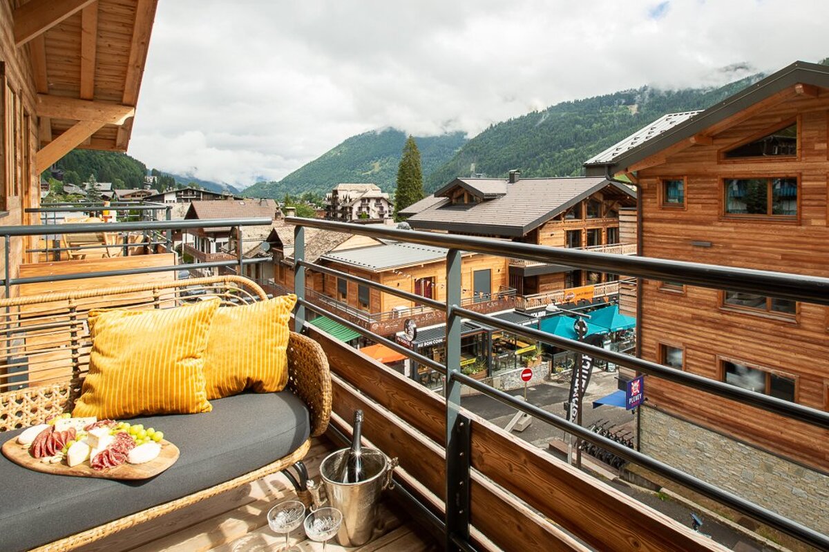 A balcony with a yellow pillow and a bucket of champagne