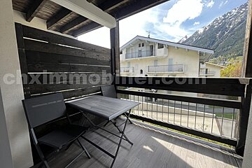A balcony with a table and chairs and the website chximmobilier.com