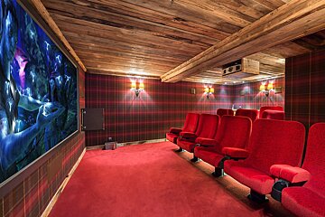 A movie theater with red seats and a large screen