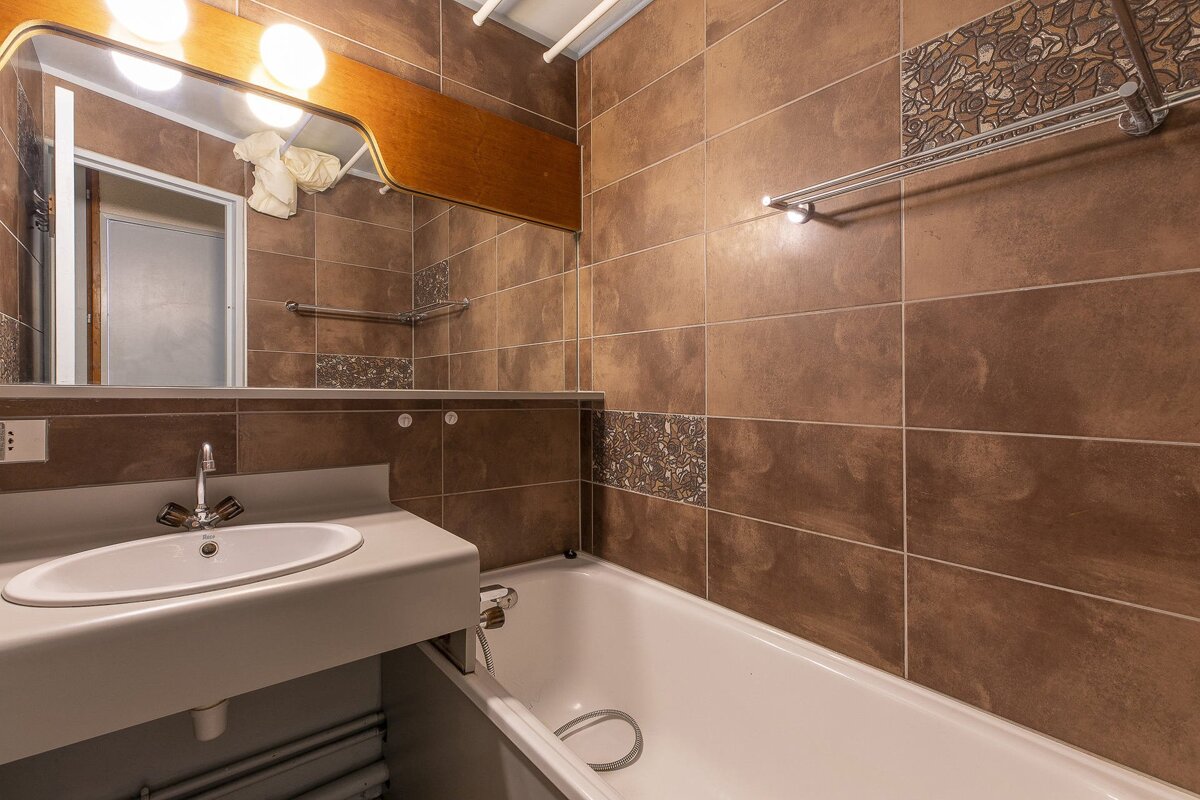 A bathroom with brown tiles and a sink and bathtub
