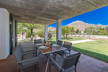 A patio with a table and chairs and a mountain in the background