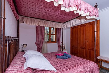 A bedroom with a canopy bed and a window