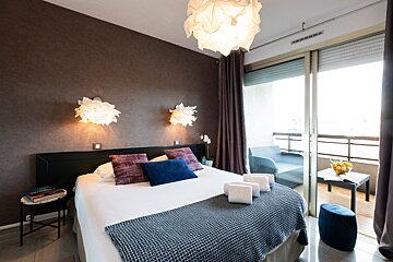 A bedroom with a sliding glass door leading to a balcony
