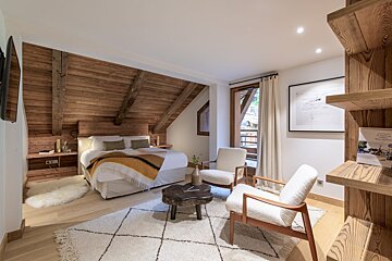 A bedroom with a large bed and two chairs