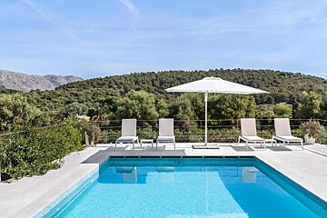 A swimming pool with chairs and a white umbrella