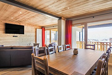 A living room with a table and chairs and a flat screen tv