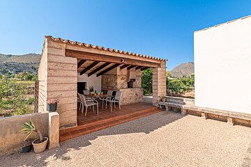 A patio with a table and chairs under a wooden roof