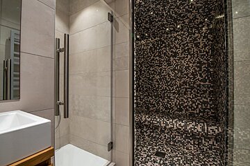 A bathroom with a walk in shower and a sink