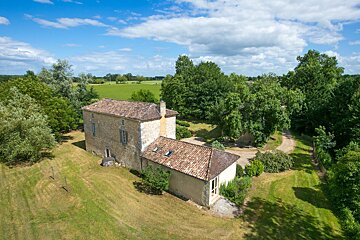 An aerial view of a house surrounded by trees and grass
