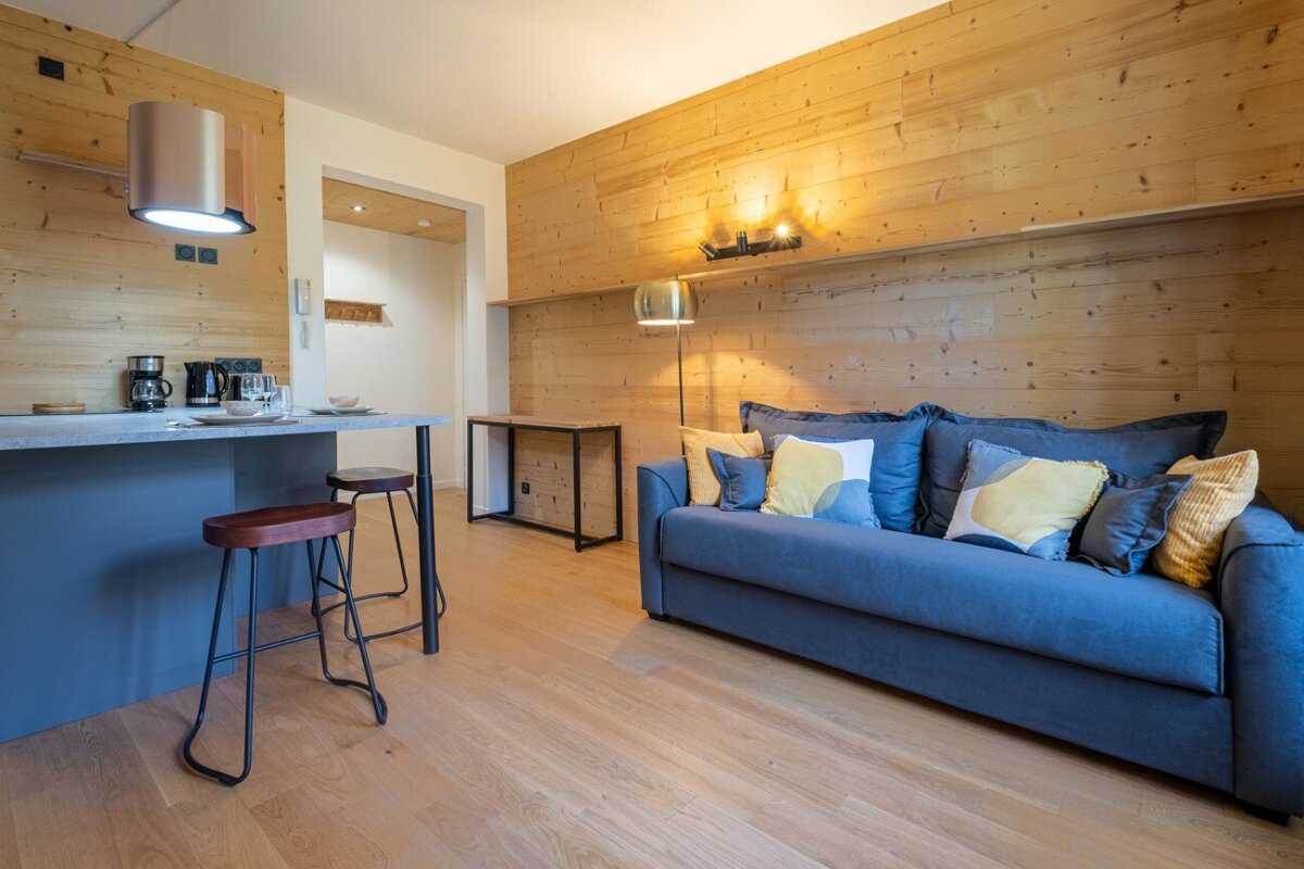 A living room with a blue couch and yellow pillows